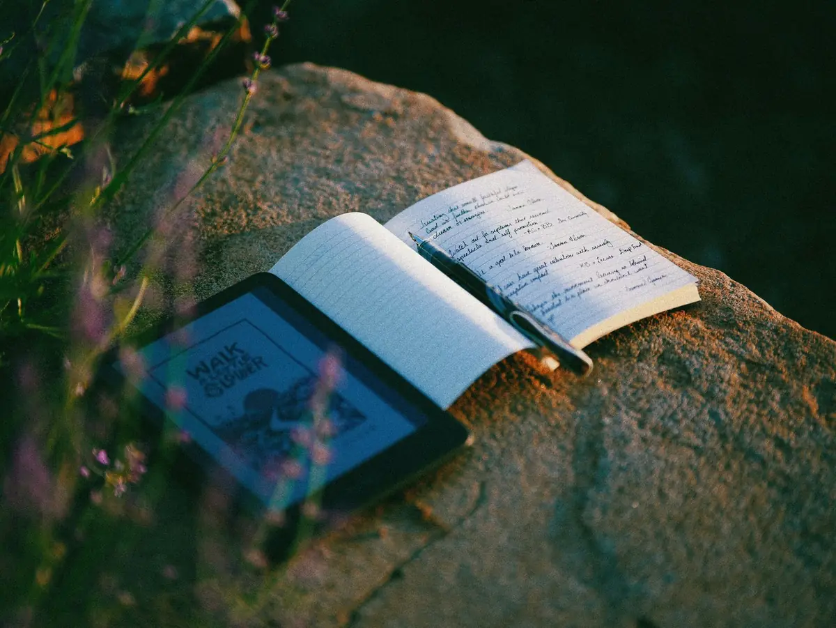 An open notebook and pen resting on a sunlit rock